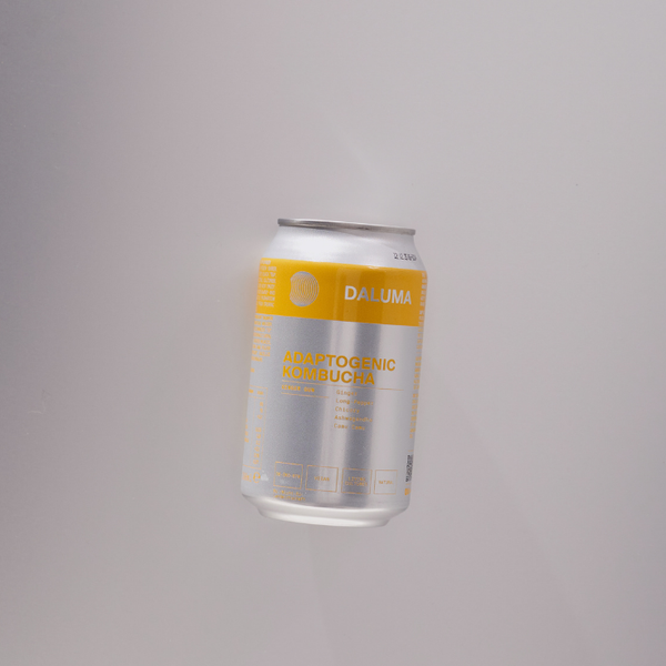 Eine silberne und gelbe Dose mit der Aufschrift Daluma Adaptogenic Kombucha steht aufrecht vor einem schlichten, hellen Hintergrund. Die Dose ist minimalistisch gestaltet und enthält einen Text, der den Geschmack und die Inhaltsstoffe des Kombuchas beschreibt.