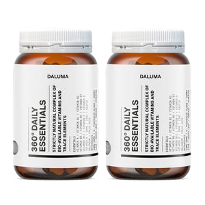 Zwei Flaschen Daluma 360 DAILY ESSENTIALS SUPPLEMENT DOUBLE mit weißen Etiketten und orangefarbenen Verschlüssen, nebeneinander auf weißem Hintergrund. Der Text auf dem Etikett ist verschwommen und unleserlich.