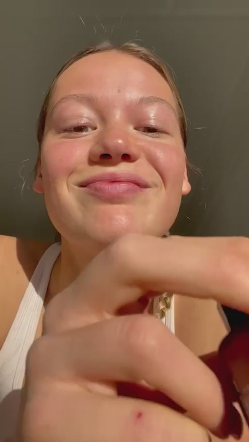 Eine Hand hält einen Tropfer mit weißem Serum über einer offenen braunen Flasche mit der Aufschrift "CELLULAR RESURGENCE SERUM" von Daluma x Eva Padberg vor einem schlichten hellen Hintergrund.