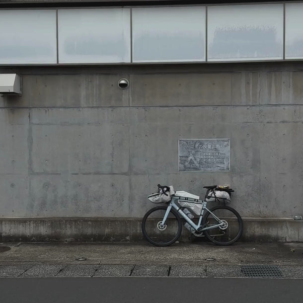 Eine Dose Daluma CLEAN BCAA ENERGY DRINK steht auf dem Bürgersteig vor einer grauen Betonwand mit einem Plakat und einer Überwachungskamera darüber, die eine urbane, minimalistische Atmosphäre schaffen.