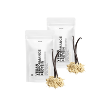 Zwei weiße DALUMA-Beutel mit der Aufschrift VEGANES PERFORMANCE PROTEIN VANILLE DOUBLE stehen aufrecht auf weißem Hintergrund, jeder neben einer Vanilleschote und einem kleinen Haufen Proteinpulver.