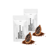Zwei weiße Beutel mit der Aufschrift DALUMA VEGANES PERFORMANCE PROTEIN KAKAO DOUBLE stehen aufrecht neben Kakaoschoten, Bio Hanfprotein und Haufen von Rohkakao auf einem weißen Hintergrund.